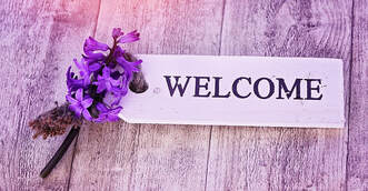Photo of purple flowers and paper that says welcome